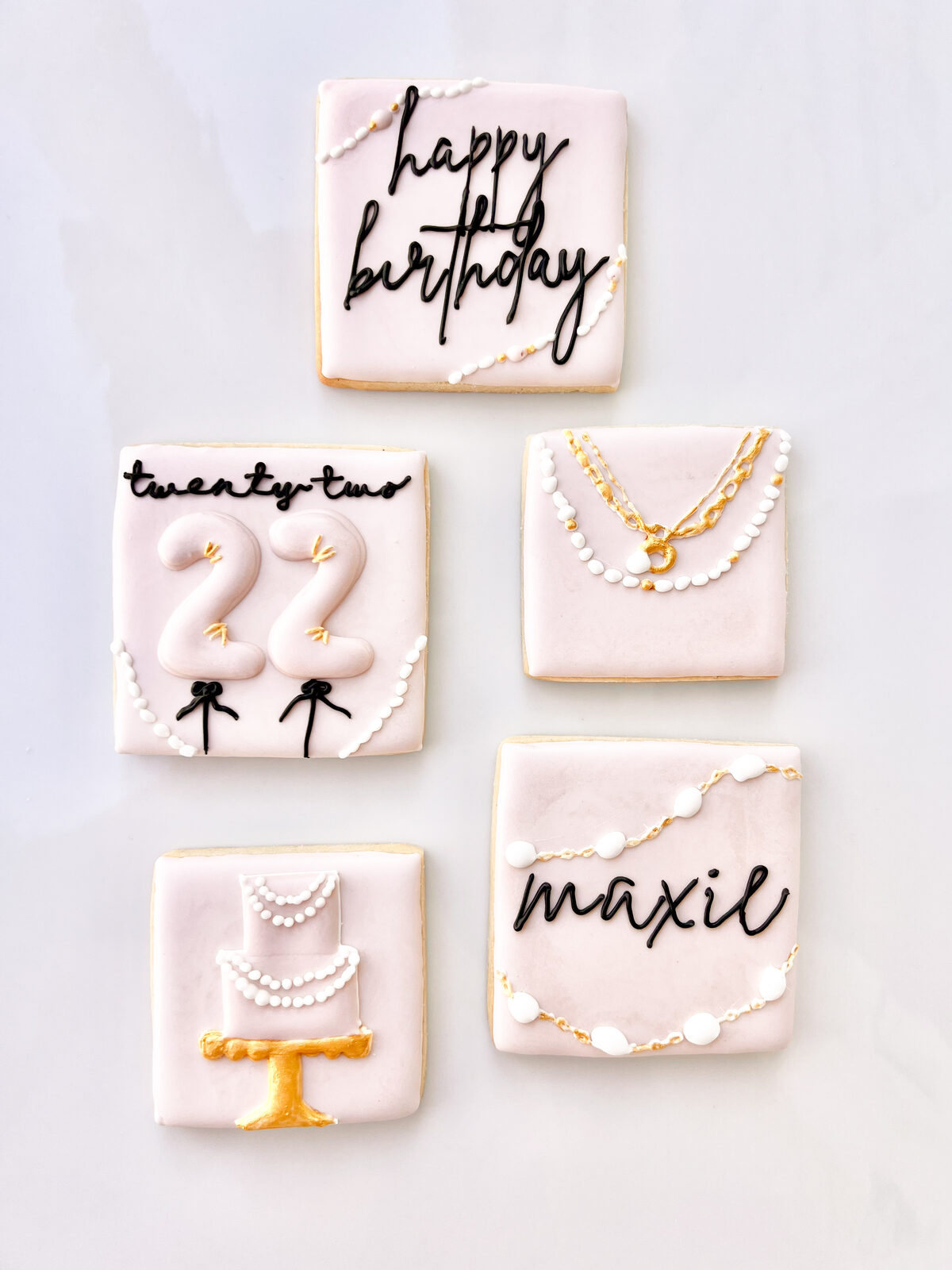 Blush pink birthday cookie set with gold jewelry details, a tiered cake, and the number 22
